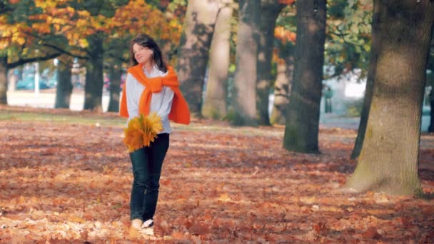 Sonbahar yaprağının tadını çıkaran genç bir kadın parka düştü. — Stok video