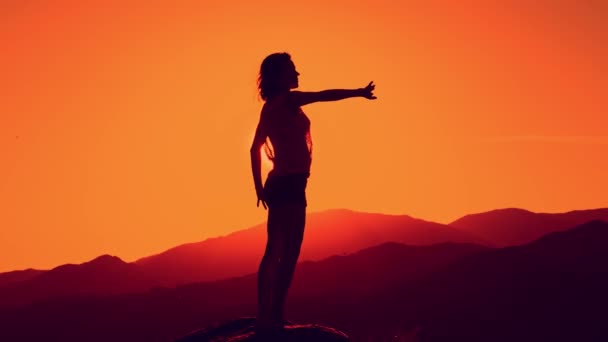 Γυναικεία σιλουέτα που χορεύει στο όμορφο ηλιοβασίλεμα, φόντο στο βουνό — Αρχείο Βίντεο