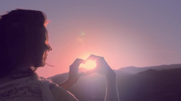 Женские руки в форме сердца на небе проходят солнечные лучи . — стоковое видео