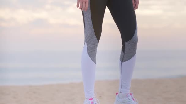 Vrouw op zoek naar gegevens over fitness horloge aan de kust na stretching oefeningen — Stockvideo