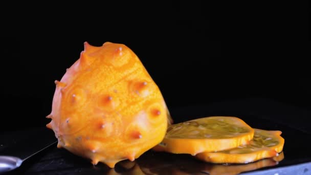Schneiden afrikanische gehörnte Melone rotierende Nahaufnahme, auf schwarzem Hintergrund — Stockvideo