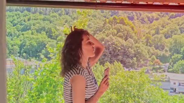 Femme dansante sur un balcon écoutant de la musique sur smartphone — Video