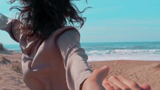 Молодая женщина ведет мужчину за руку в океан — стоковое видео