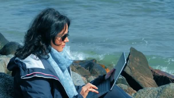 Freelancer donna seduta sulle rocce e utilizzando il computer portatile — Video Stock