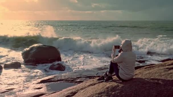 Young woman taking picture of rocky coast of atlantic ocean on smartphone — Stock Video