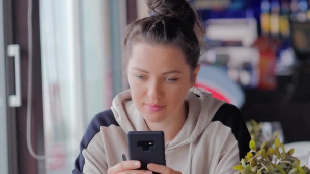 Όμορφη γυναίκα μηνυμάτων με το κινητό της στο καφέ — Αρχείο Βίντεο