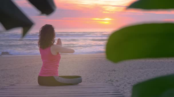 Mujer joven que medita en el paseo de madera en la orilla del océano — Vídeo de stock