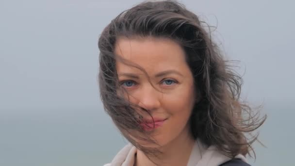 Portret van een vrouw met blauwe ogen op het strand tijdens regenachtige dagen. — Stockvideo