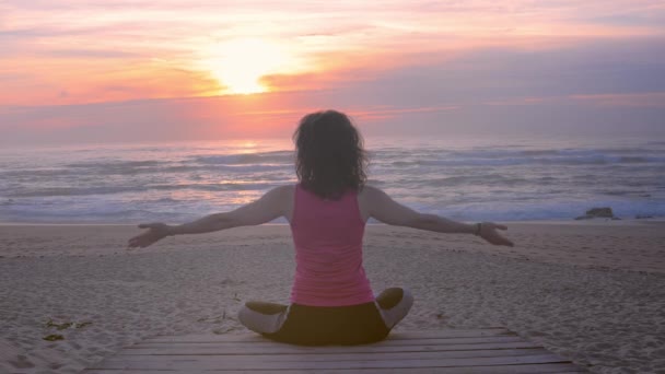 Mujer joven que medita a pie de madera en la playa del océano — Vídeos de Stock