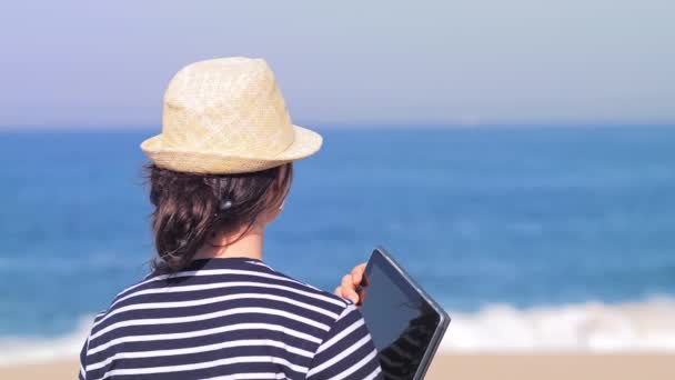 Reizende vrouw in strohoed op strand met laptop op vakantie — Stockvideo