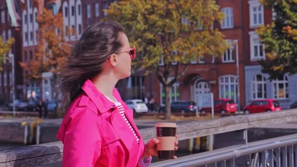 Atractiva mujer en gafas de sol tomando café y disfrutando de vistas a la ciudad. — Vídeo de stock