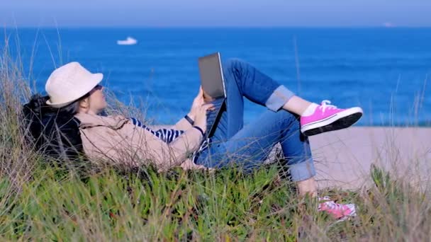 Szabadúszó nő feküdt a tengerparton homok és gépelés szöveg a jegyzetfüzetében — Stock videók
