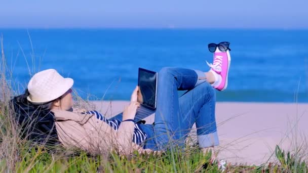 Mujer acostada en la arena y charlando en línea en la playa — Vídeo de stock