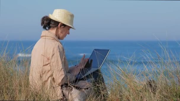 해변에 있는 공책에 앉아 있는 프리랜서 여자 — 비디오