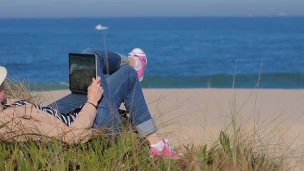 해변의 모래 위에 누워 수첩에서 일하는 프리랜서 여성 — 비디오