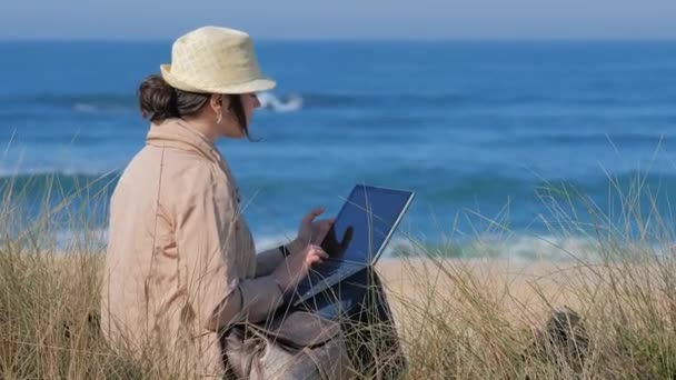 Mulher taxando em seu caderno na praia ensolarada — Vídeo de Stock