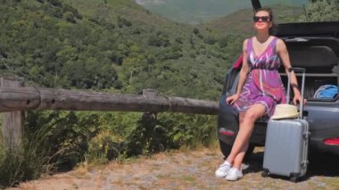 Bavullu bir kadın arabayla seyahat etmeye hazır.