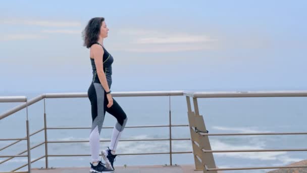 Активная фитнес-женщина на берегу моря делает упражнения на растяжку — стоковое видео