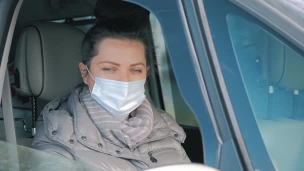 Mujer en coche con máscara quirúrgica en la ventana de apertura de la cara del coche. COVID-19 Coronavirus — Vídeo de stock