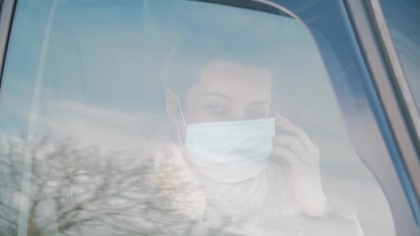 Frau im Auto mit Chirurgenmaske im Gesicht öffnet Autoscheibe, Sicherheitszulage. — Stockvideo