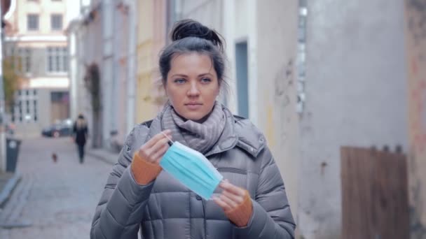 Frau in Stadtstraße mit OP-Maske im Gesicht gegen Coronavirus 2019. — Stockvideo