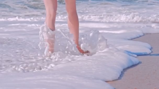 Femme marchant sur la plage de sable avec des vagues mousseuses de l'océan . — Video