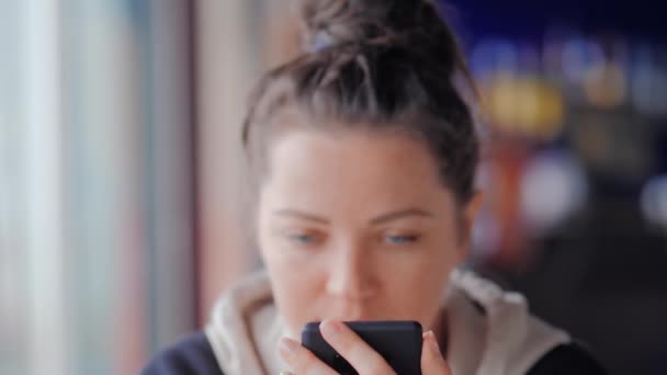 Όμορφη γαλανομάτα γυναίκα γραπτών μηνυμάτων με το κινητό της στο καφέ — Αρχείο Βίντεο