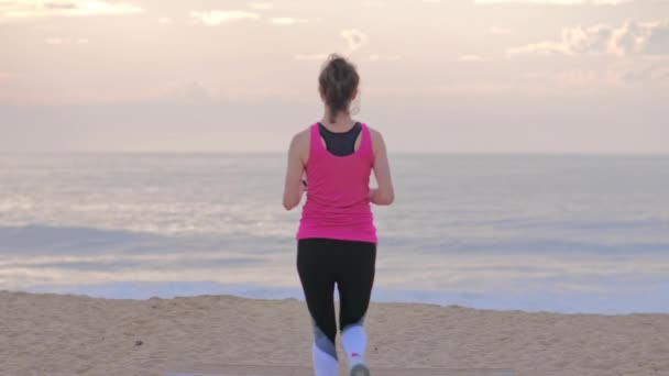 Woman runner on the seashore running and looking on fitness watch. — Stock Video