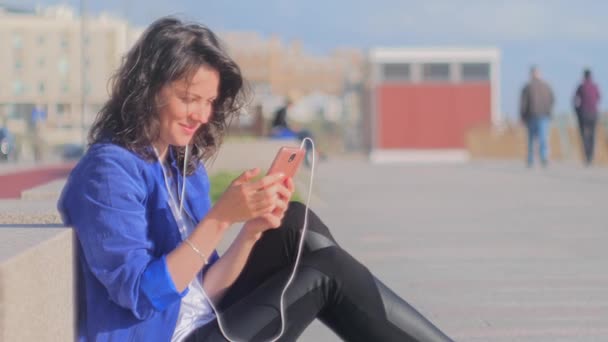 Glad leende ung kvinna lyssnar på musik med mobilen. — Stockvideo