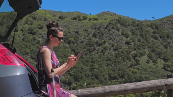 Mujer viaja en coche, planea su viaje con el teléfono inteligente en sus manos — Vídeo de stock