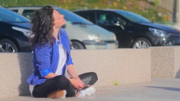 Usmívající se mladá žena poslech hudby pomocí mobilních na ulici. — Stock video