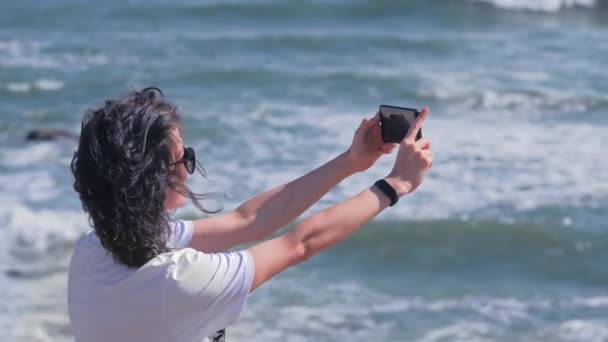 Lycklig kvinna tar bilder av havet med smartphone kamera — Stockvideo