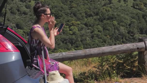 Mujer viaja en coche en el paisaje de montaña, planea su viaje con el teléfono inteligente — Vídeo de stock