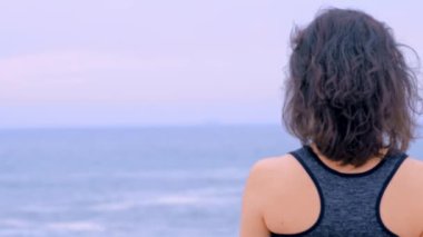 Plajda koşan kadın egzersiz yapıyor ve spor saatleri hakkında bilgi topluyor.