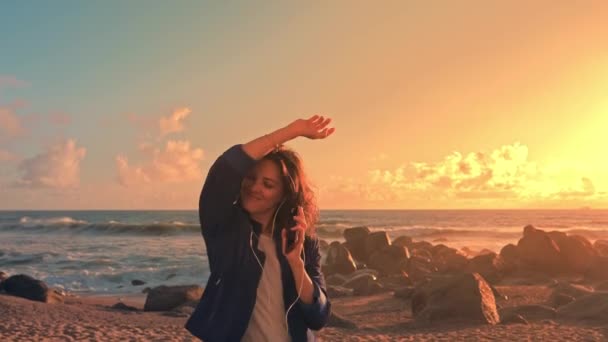 Mujer joven y feliz bailando escuchando música usando un smartphone . — Vídeo de stock