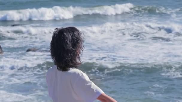 Mujer joven meditando en posición de loto sobre rocas en la orilla del mar — Vídeo de stock