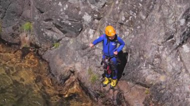 Turist çocuk dağ şelalesinin gölüne dalıyor.