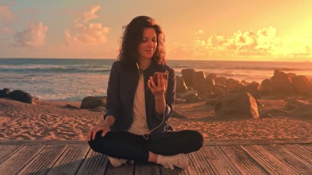 Šťastná mladá žena poslouchá hudbu pomocí mobilu. — Stock video