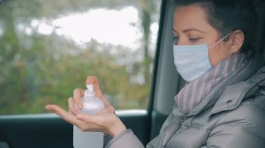 Yüz dezenfekte eden elleri cerrahi maskeli bir kadın..