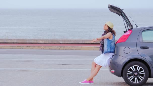 Γυναίκα ταξιδεύει με αυτοκίνητο, χαλαρώνει στην παραλία, σηκώνει τα χέρια ψηλά — Αρχείο Βίντεο