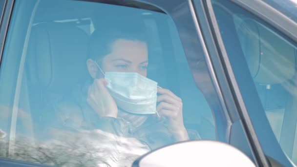Frau im Auto setzt Gesichtsschutzmaske auf und öffnet Autoscheibe Coronavirus — Stockvideo