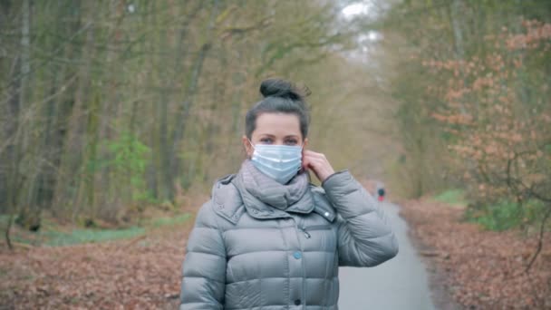 Woman in forest removes the protective mask from face and smiles — Stock Video