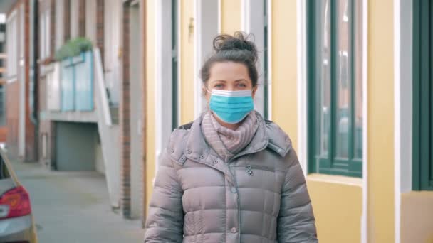 Mujer en la calle de la ciudad quita la máscara protectora de la cara y sonríe — Vídeos de Stock