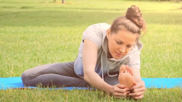 Mujer joven practicando estiramiento ejercicio de yoga en la naturaleza — Vídeo de stock