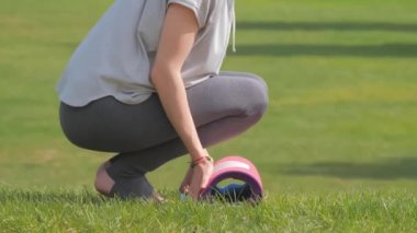 Yeşil çimenler üzerinde egzersiz yapmadan önce kadın yoga minderini yuvarlıyor.