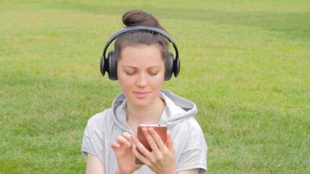 Hermosa mujer en auriculares con smartphone escuchando música — Vídeo de stock