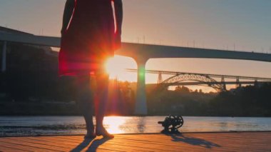 İskelede kırmızı elbiseli genç bir kadın gün batımında Porto 'nun manzarasına hayran.