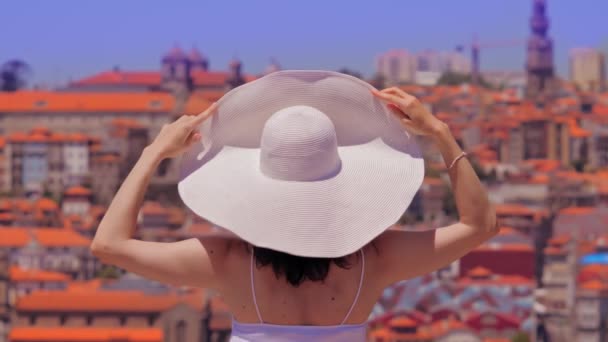 Mulher turista de chapéu branco grande apreciando paisagem urbana da Cidade do Porto. Visão traseira — Vídeo de Stock