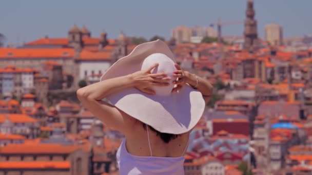 Jonge vrouw toerist in de zomer hoed genieten van stadsgezicht van Porto. Achteraanzicht — Stockvideo