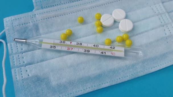 Blauw medisch masker en thermometer masker en pillen. Medisch concept op witte achtergrond — Stockvideo